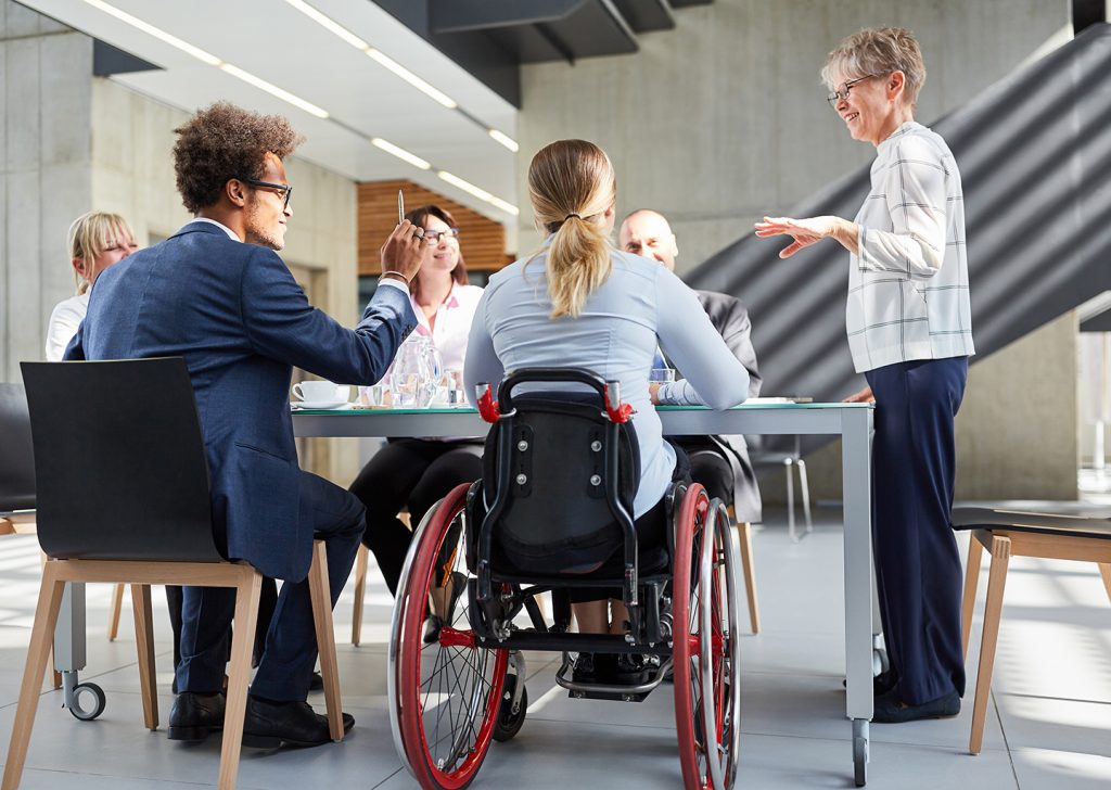 Manager inclusivo guida una riunione, promuovendo diversità e inclusione in azienda per una cultura equa e collaborativa.